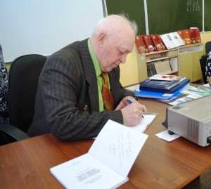 Подписывает книги.
